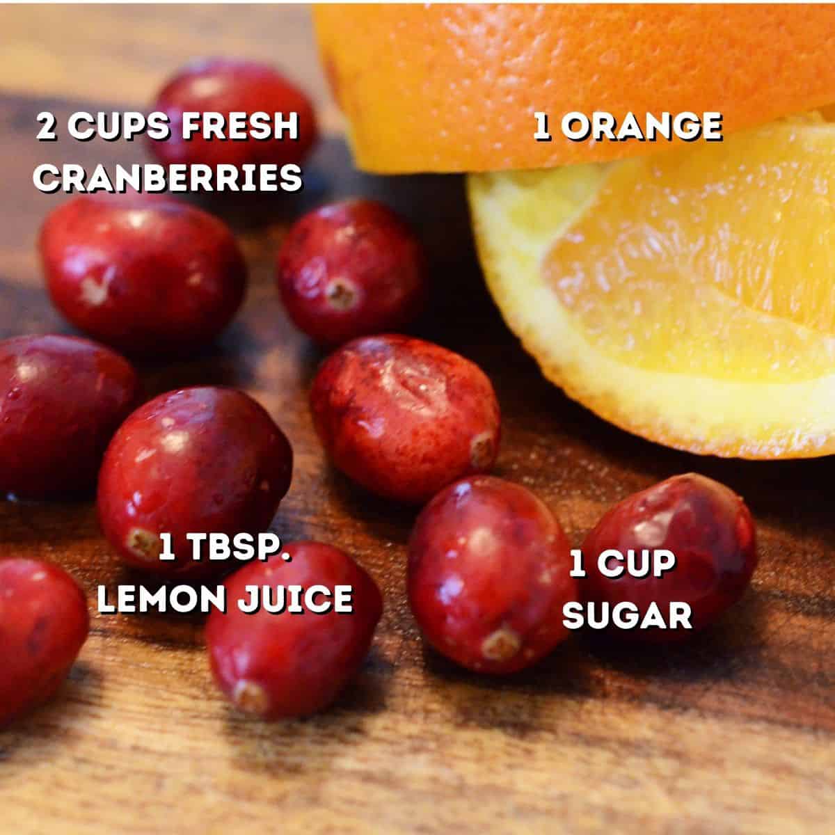 Some fresh cranberries and a cut-up orange on a cutting board.