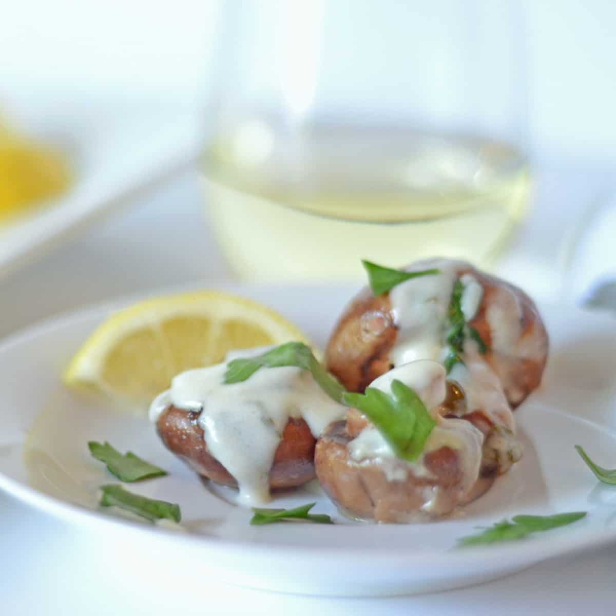 A plate of mushrooms with cream and parsley slathered over them.