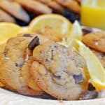 A bunch of chcooatle chunk cookies with orange wedge garnishes.
