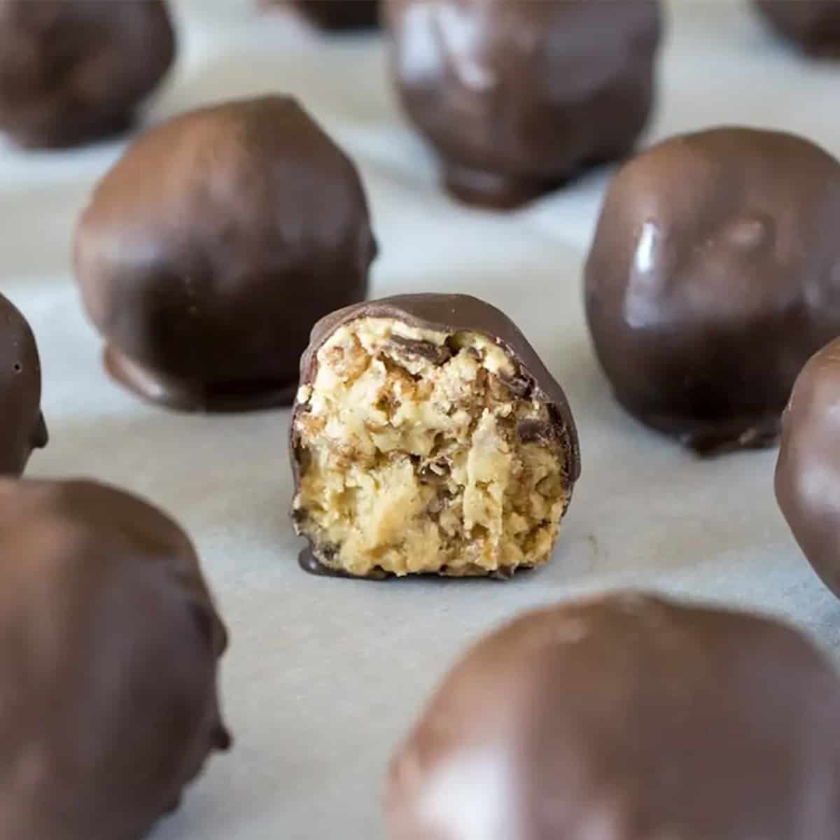 A bunch of peanut butter balls with a bite taken out of one of them.