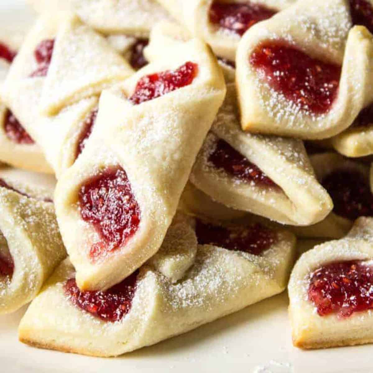 A pile of pastry turnovers with red jam oozing out of them.