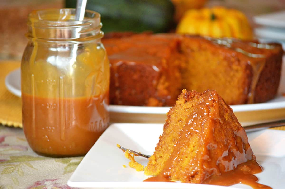 A pumpkin cake with a jar of caramel sauce.