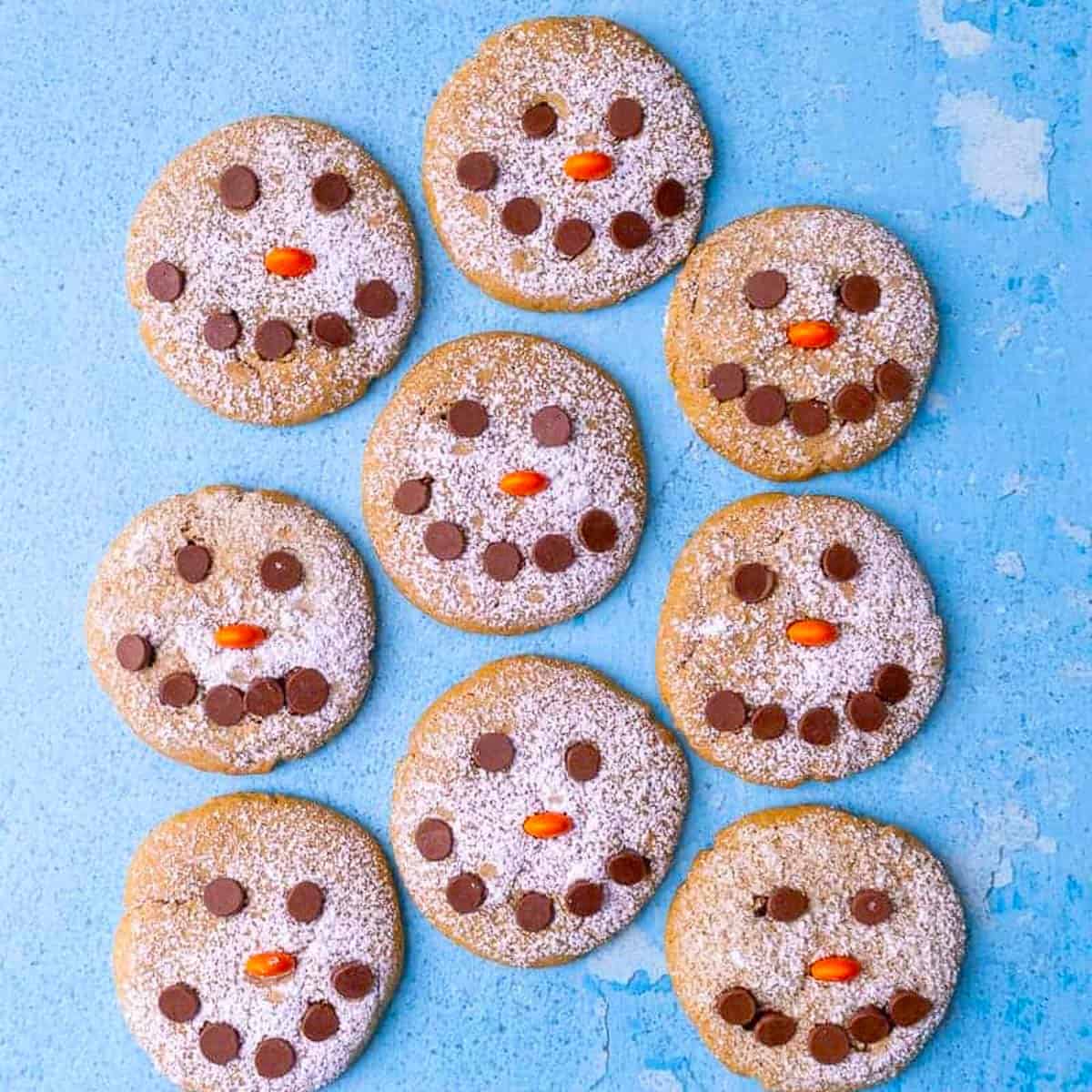 A bunch of round cookies with chocolate chips shaped like eye and a smile.