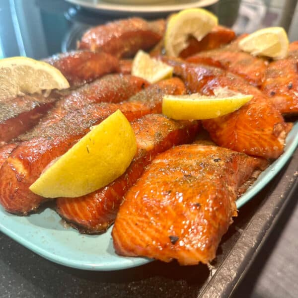 A platter of freshly smoked salmon with lemon wedges on top.