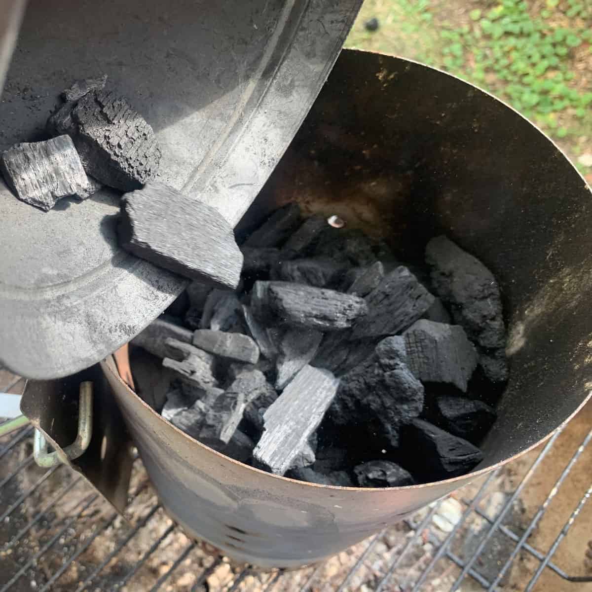 Dumping lump charcoal into a charcoal chimney.