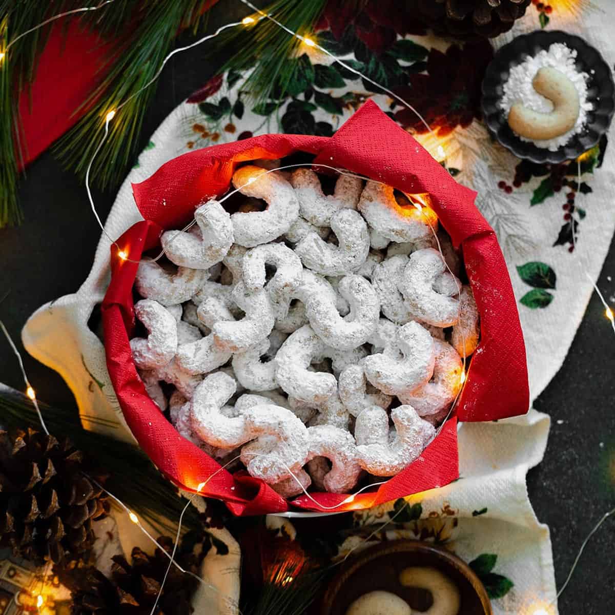 A bunch of crescent-shaped cookies in a holiday tin.