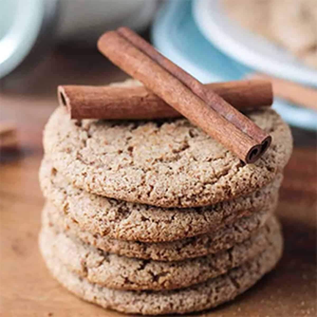 A stack of light brown cookies with cinnamon sticks on top.