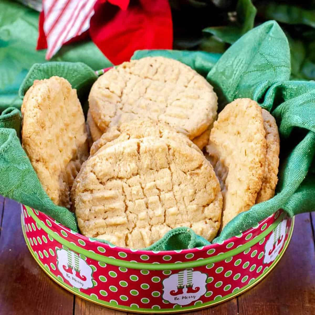 A holiday tin of cookies on a green towel.