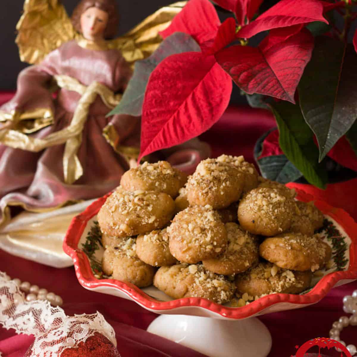 A plate of cookies on a holiday platter with a poinsettia in the back ground.