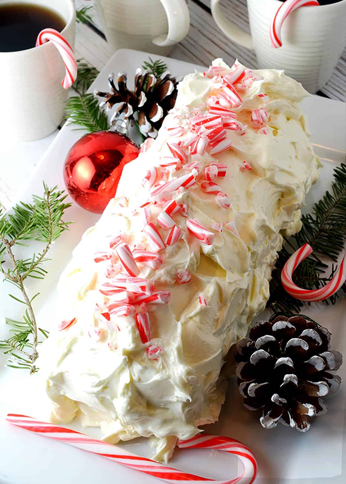 A festive log-shaped cake with white frosting and candy canes on top.