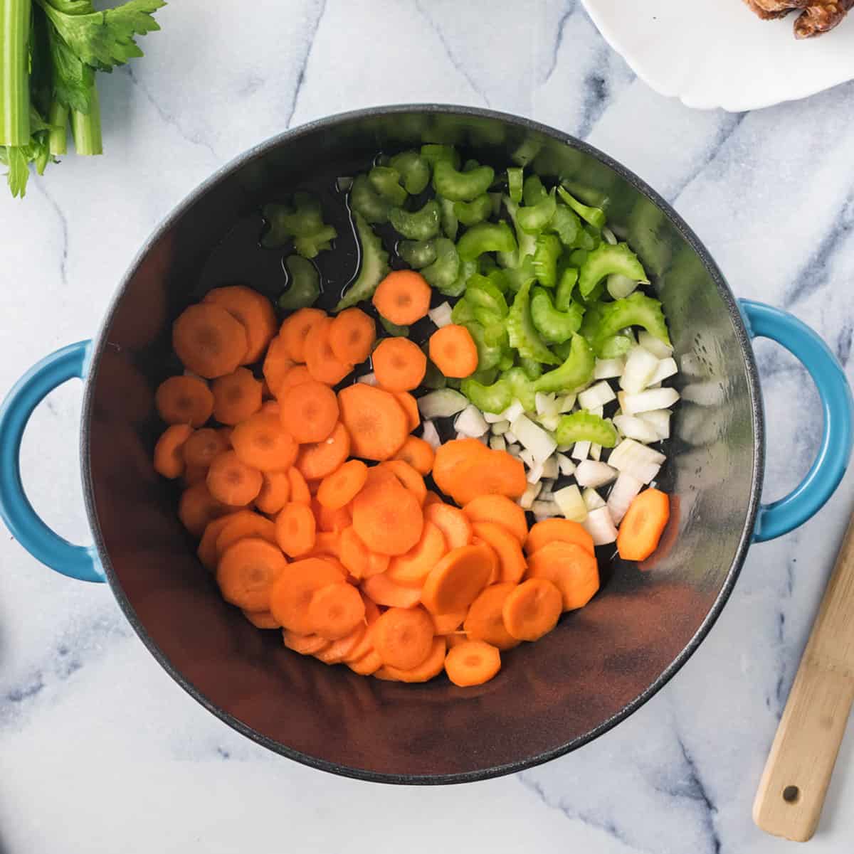 A pot of cut carrots, onion, and celery for a mire poix.
