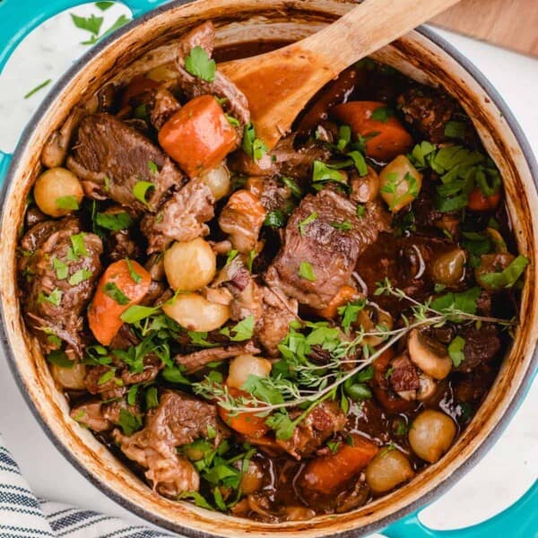 A pot of beef bourguignon with a wooden spoon.