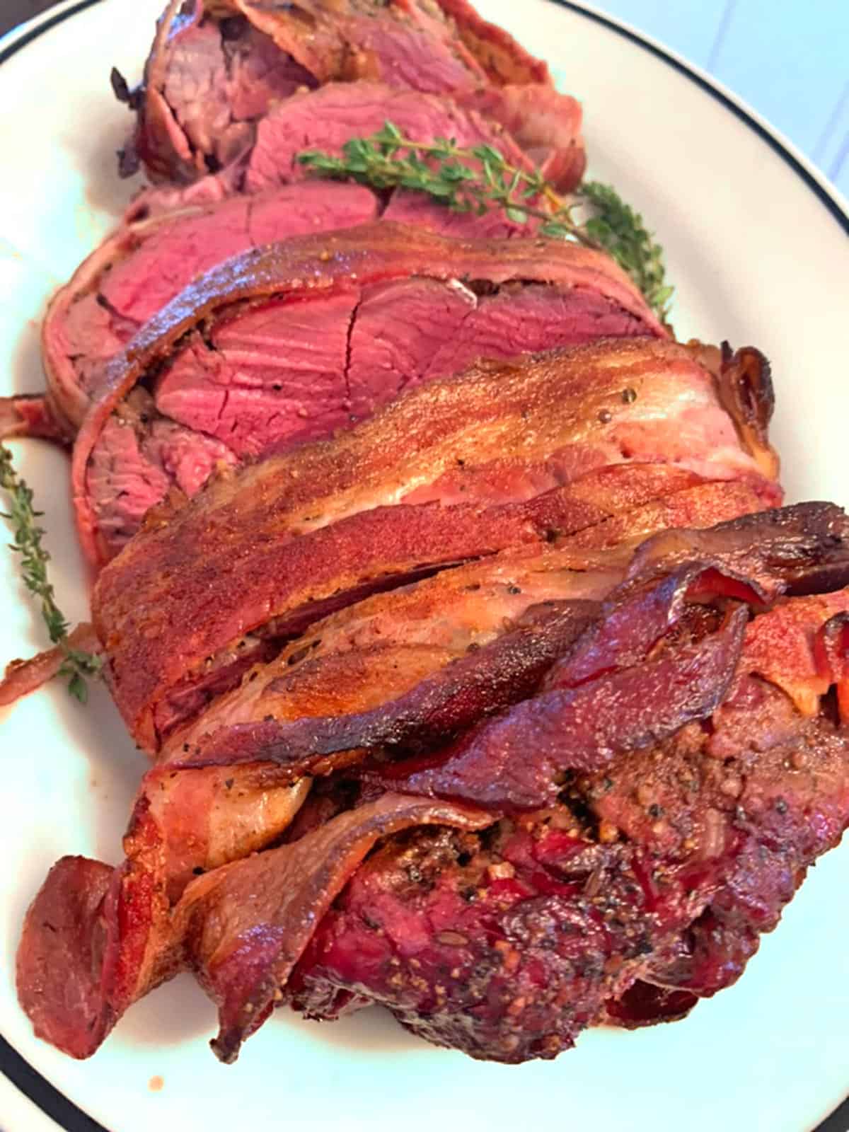 A plate of beef tenderloin wrapped in bacon, sliced and done medium-rare.