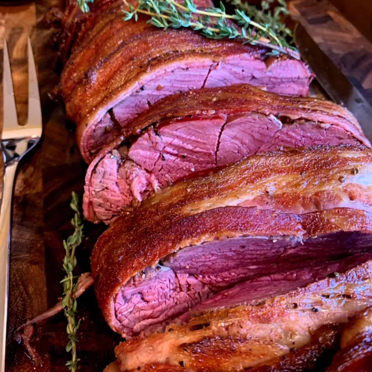 A sliced beef tenderloin that's wrapped in bacon and done to medium-rare.