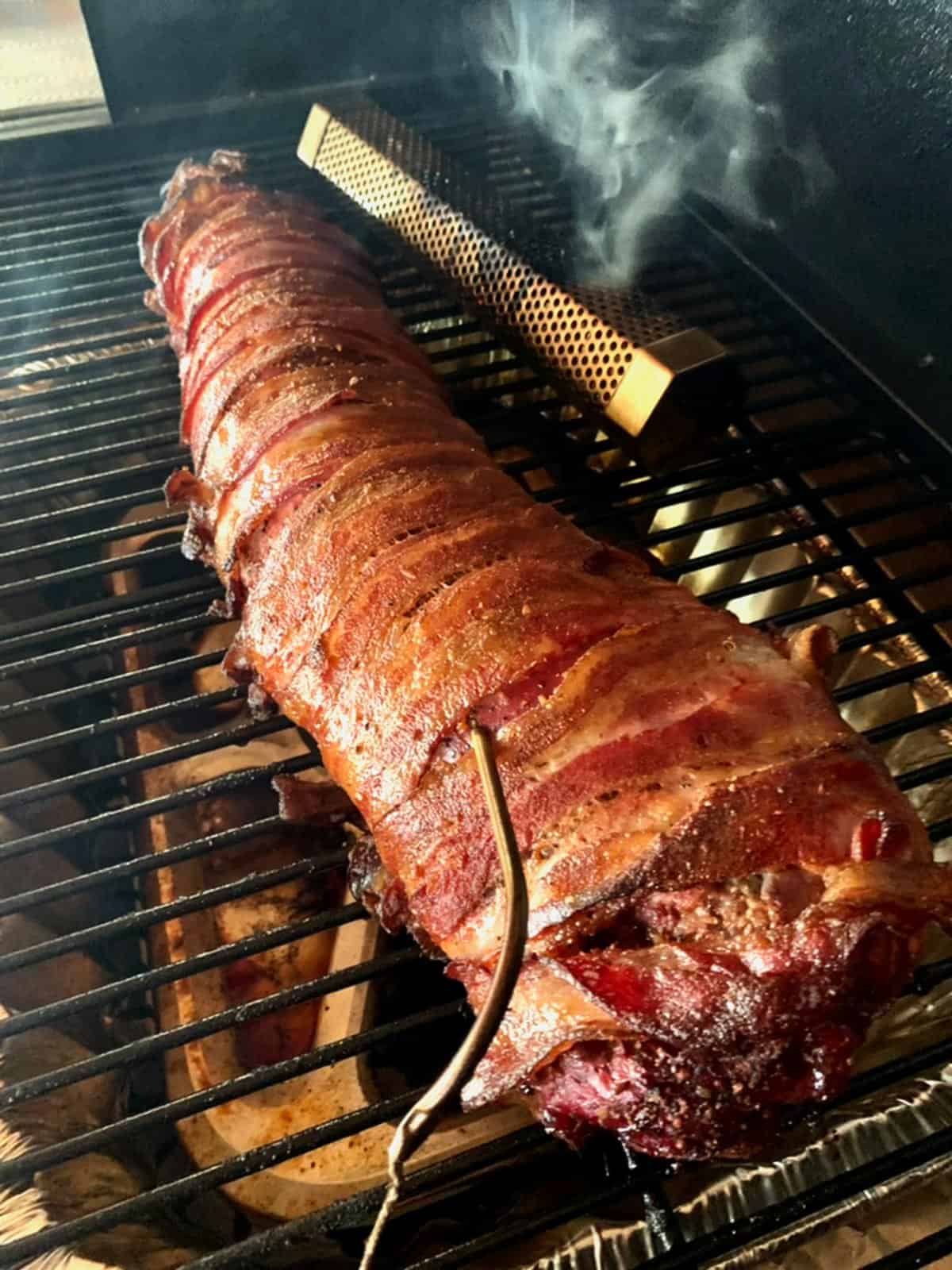 A smoked beef tenderloin sitting on a pellet smoker with a smoke tube.