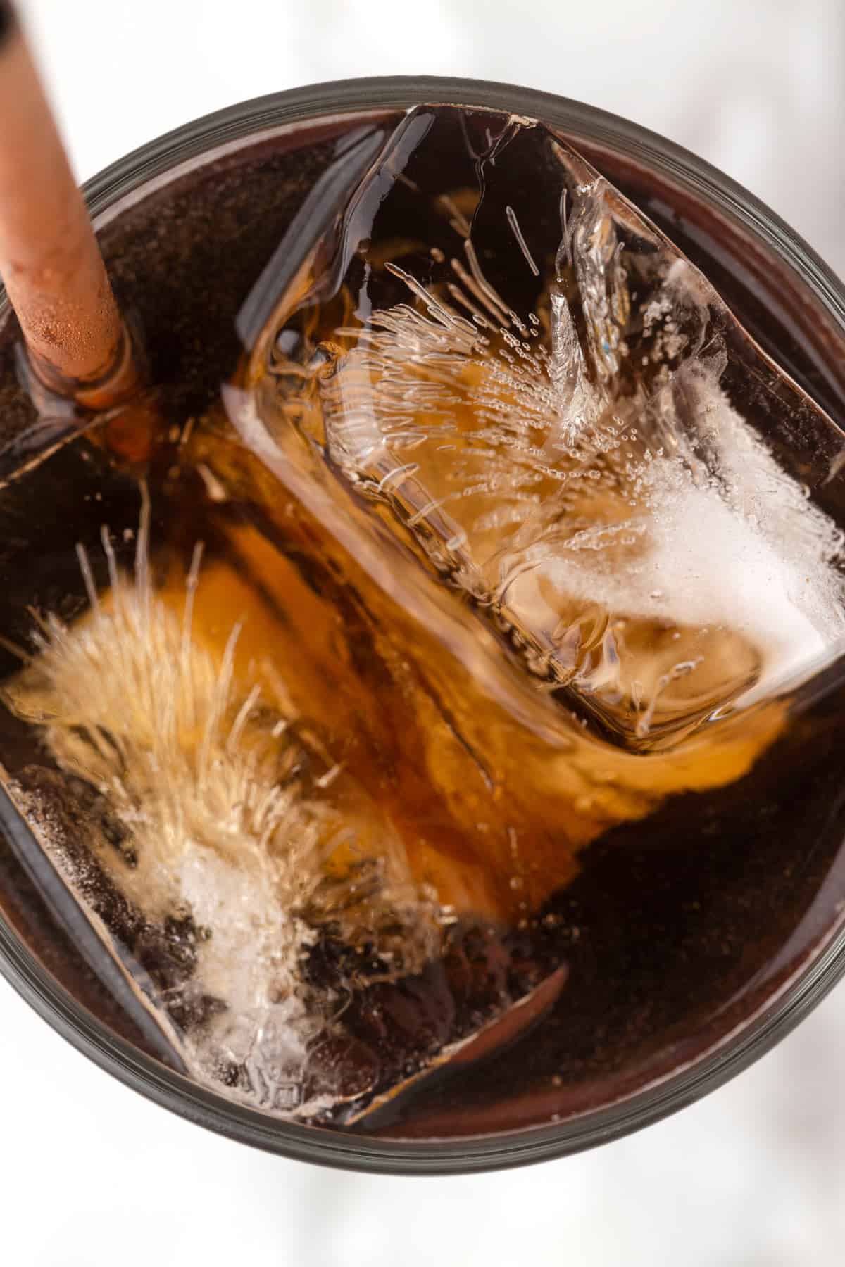 Overhead view of a glass of coke with ice and a straw.