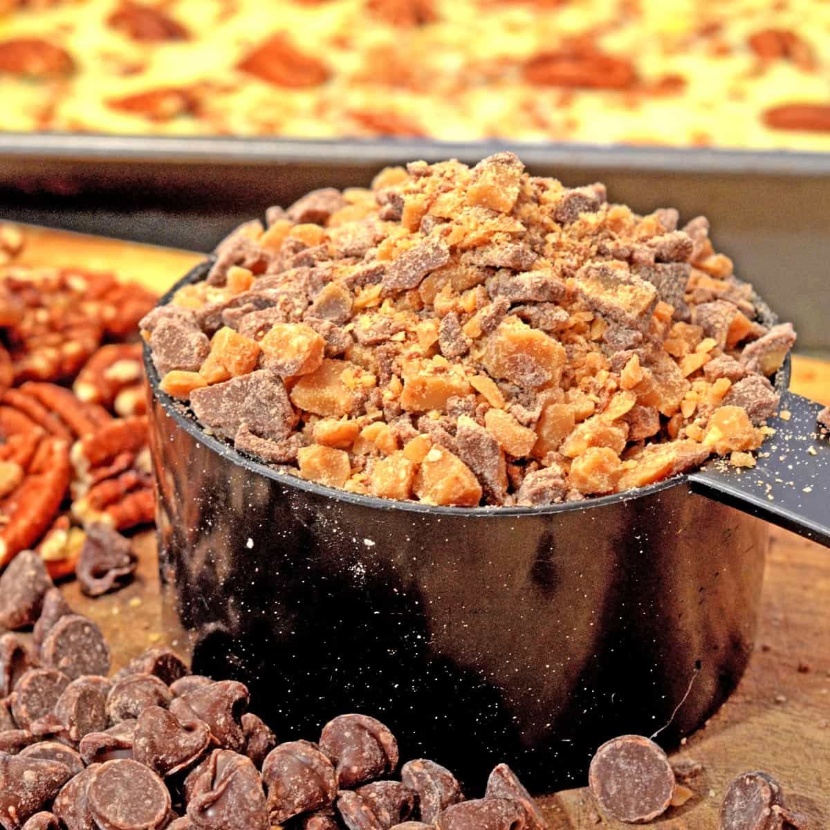 A measuring cup filled with toffee and chocolate bits.