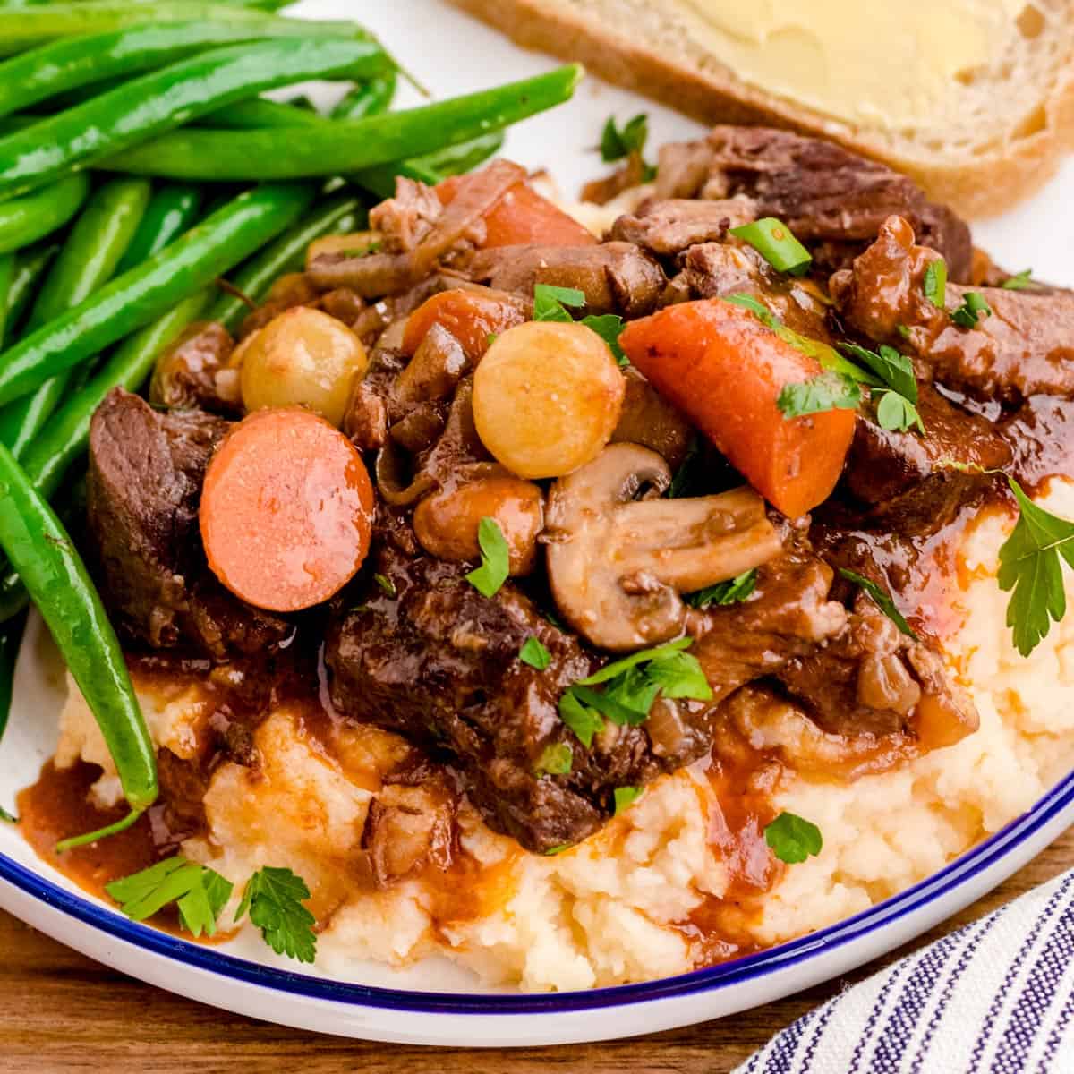 A plate of beef bourguignon over mashed potatoes.