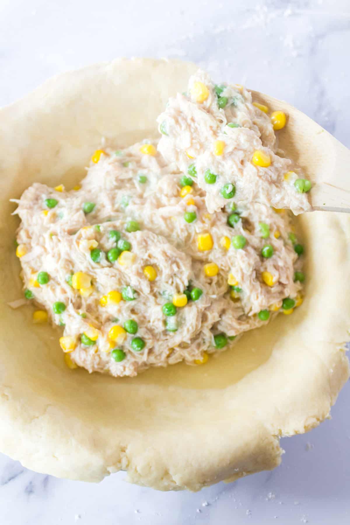 Adding pot pie filling to a pie pan.