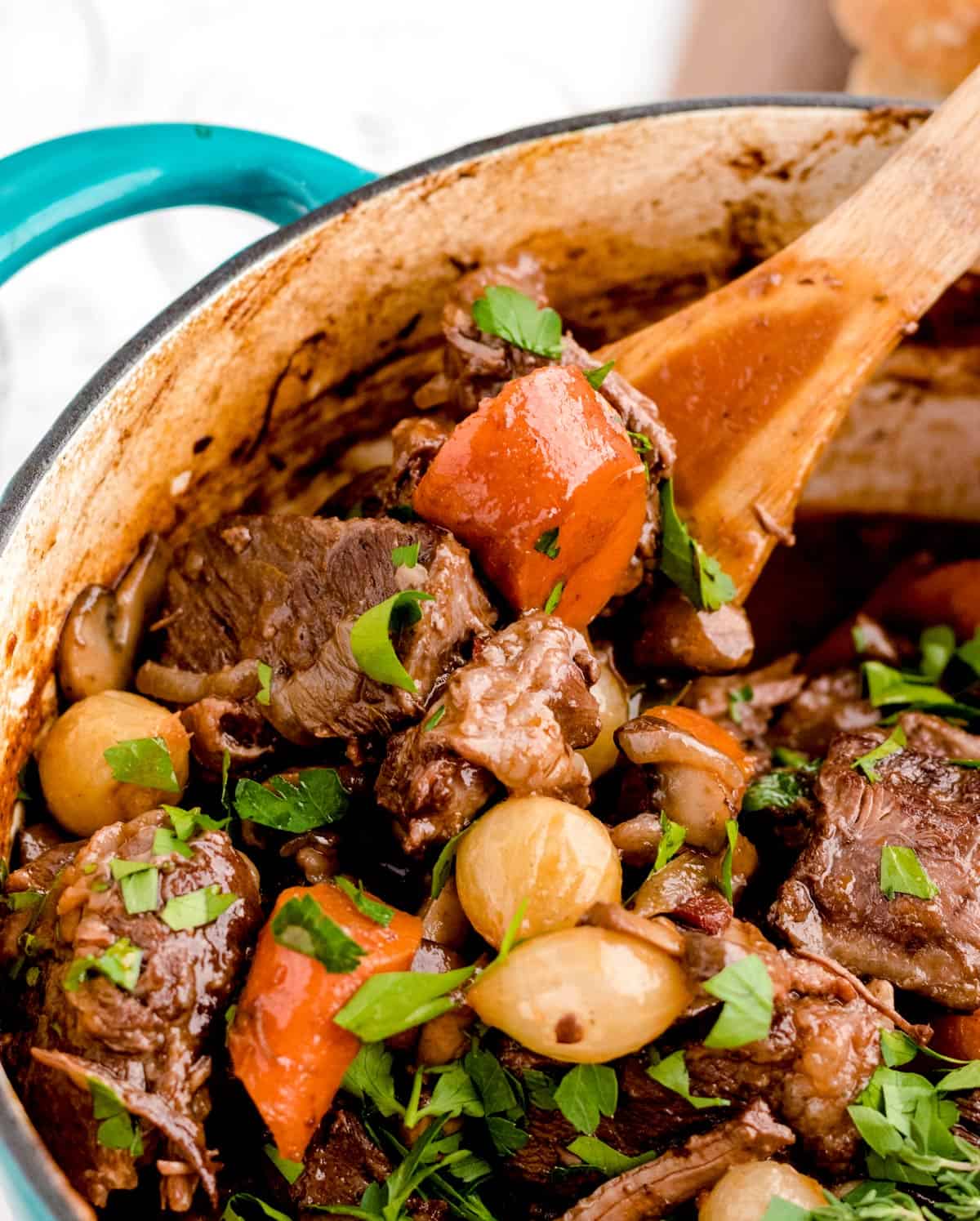 Stirring a pot of beef stew with a wooden spoon.