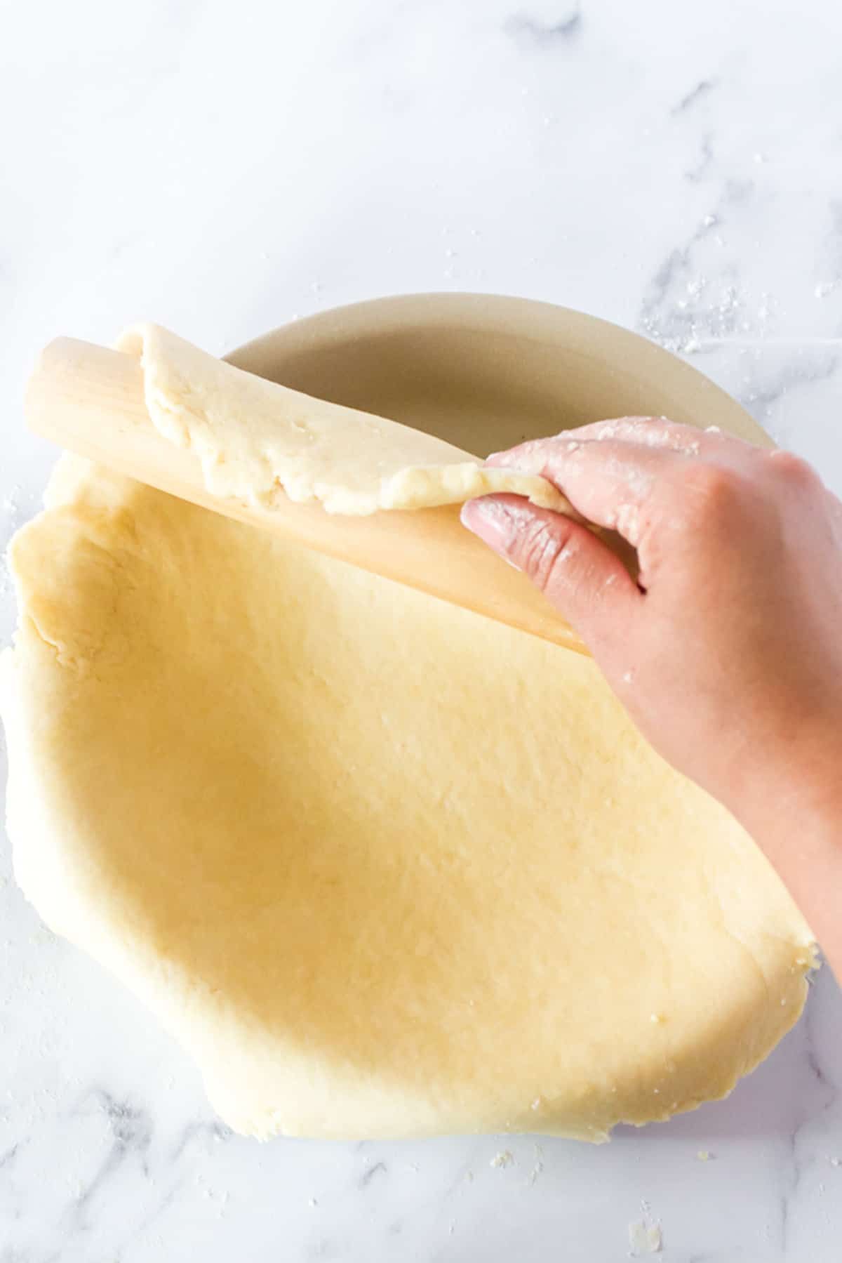 Slipping a dough from a rolling pin to a pie plate.