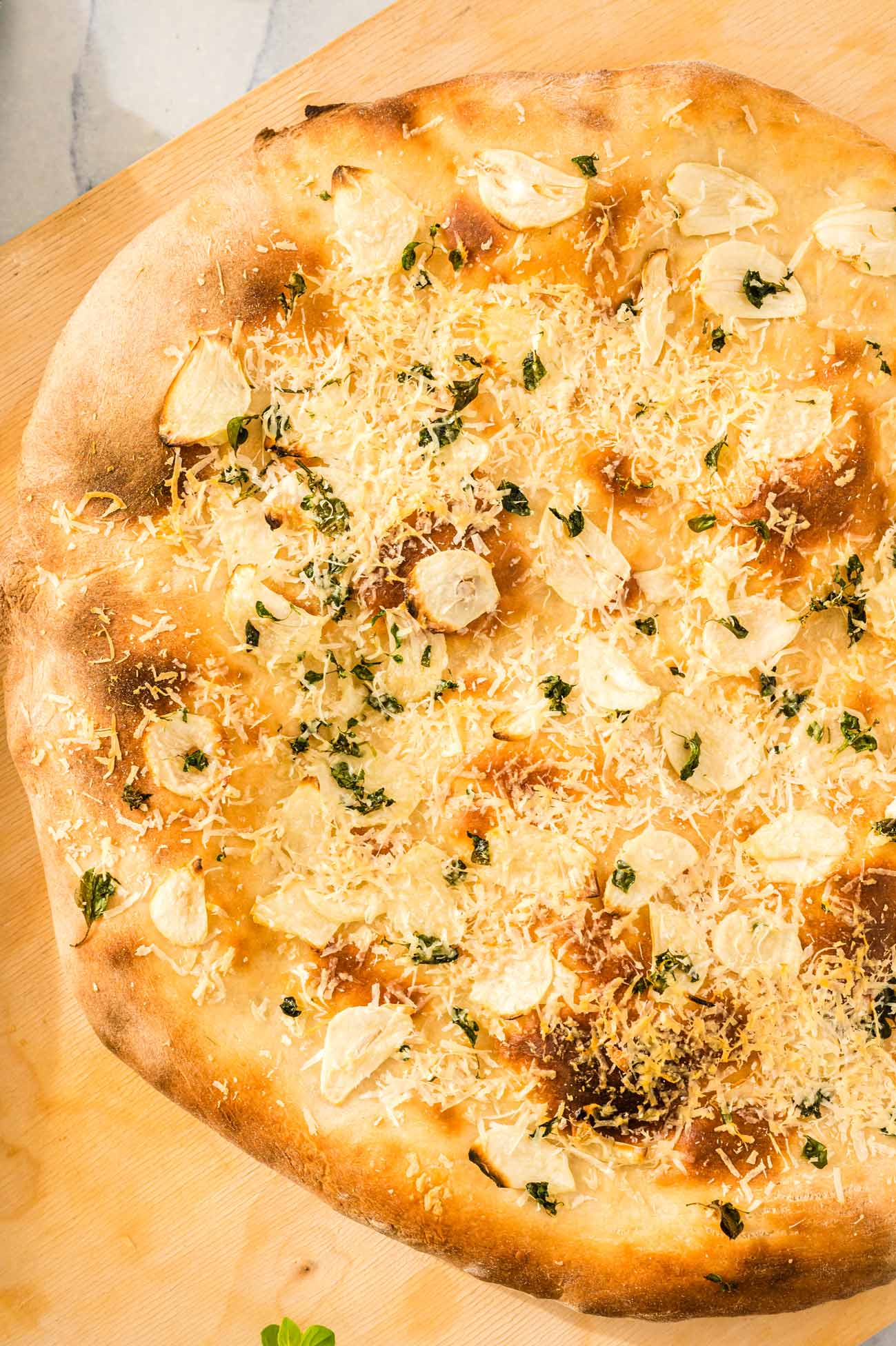 A freshly baked garlic pizza on a cutting board.