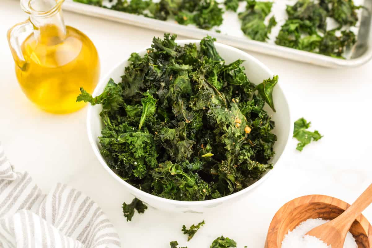 A bowl of kale chips and a jar of olive oil.