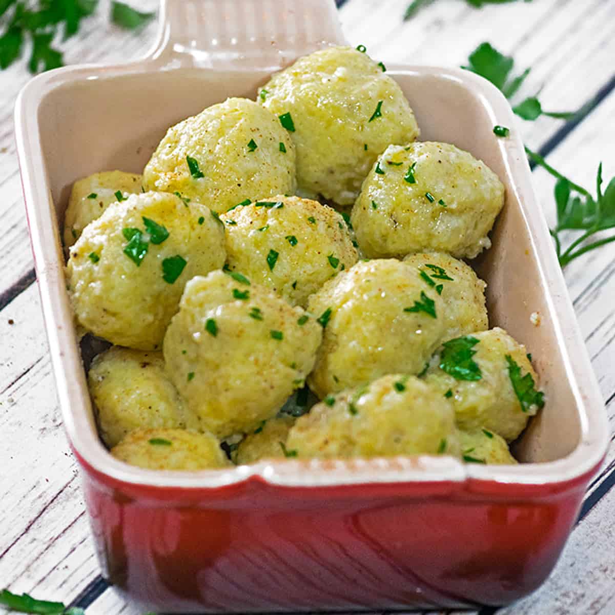 A pan of potato dumplings garnished with parsley.
