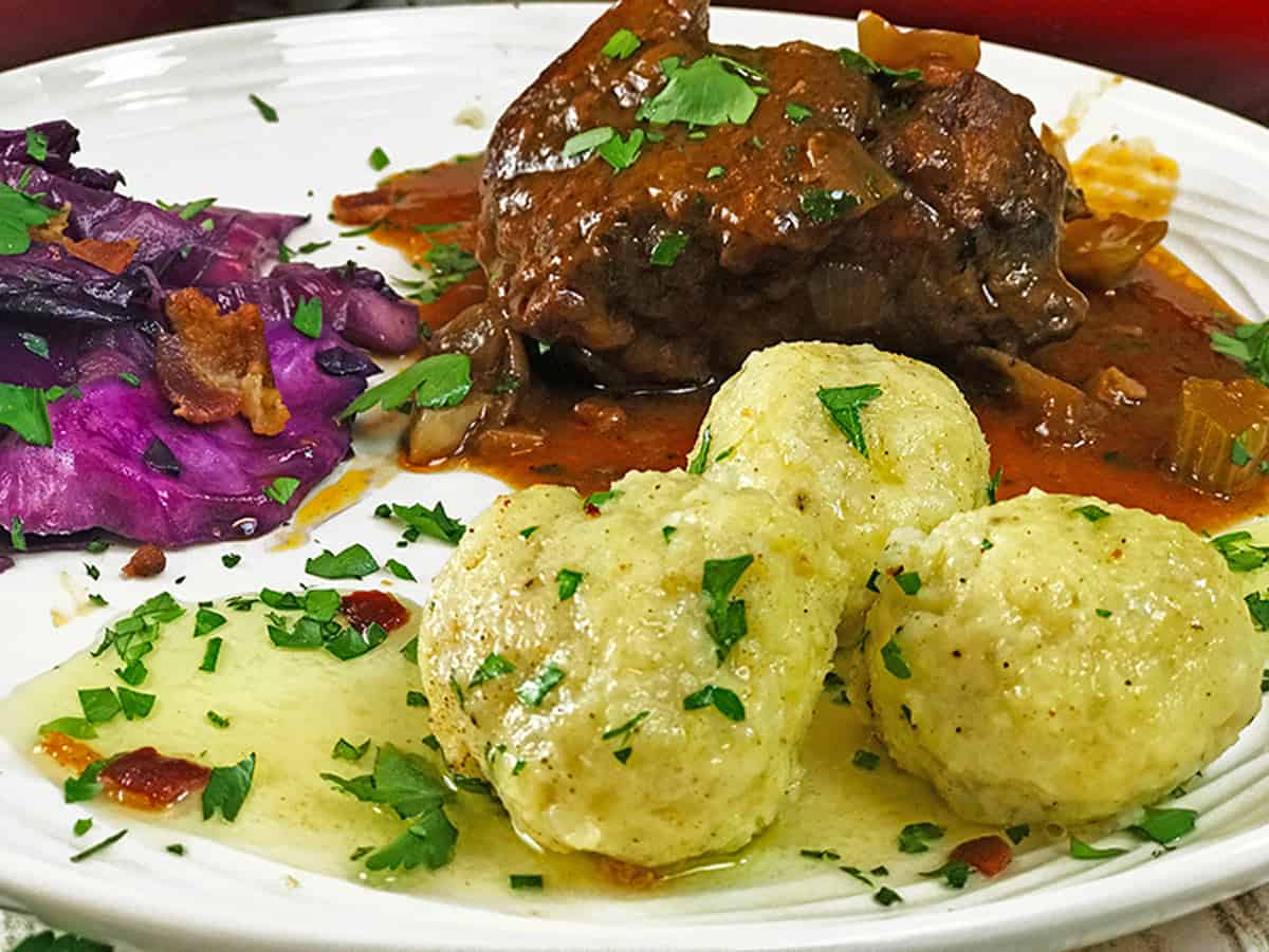 Plate of potato dumplings, braised pork, and fried cabbage.