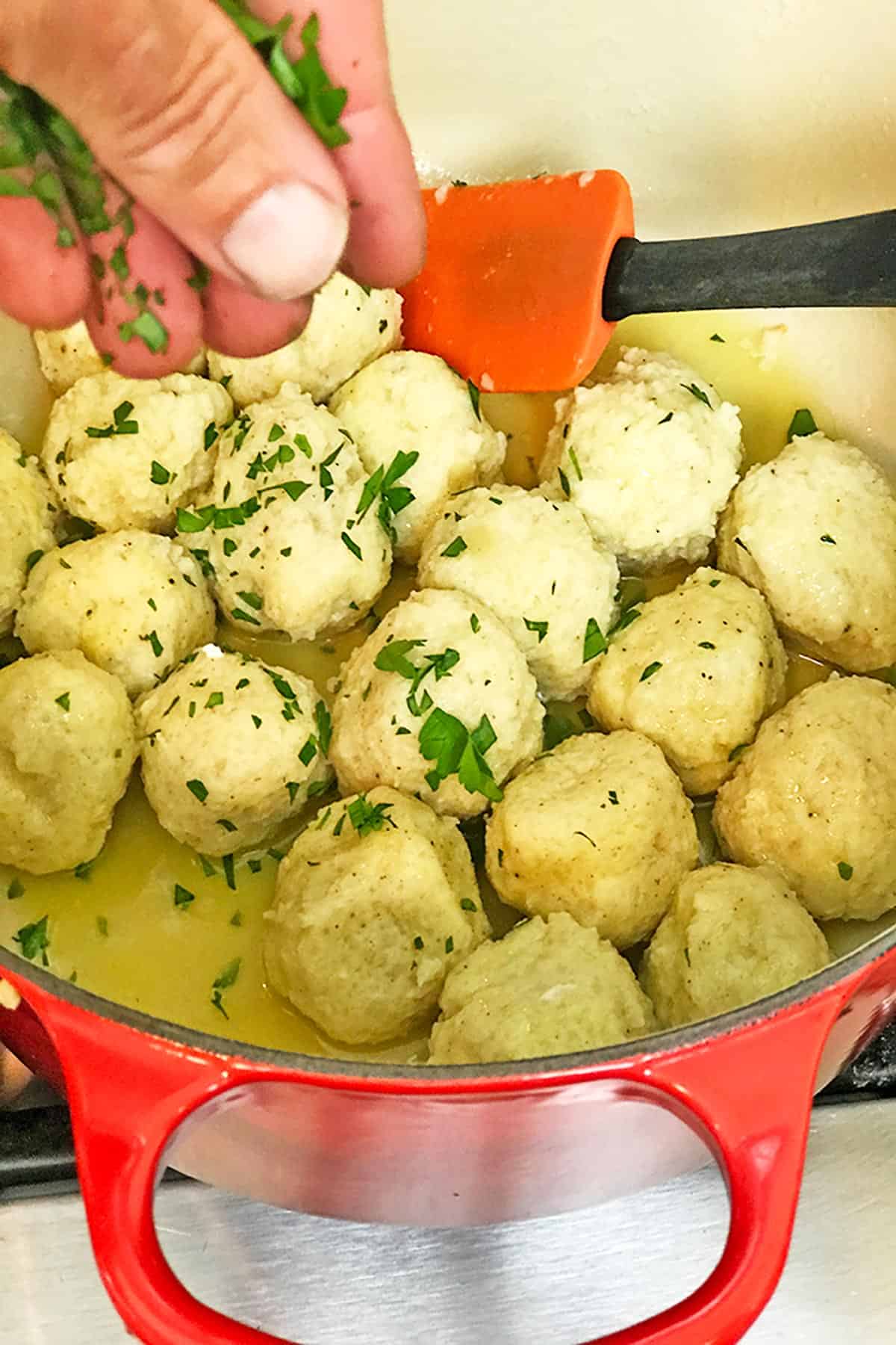 Adding some fresh herbs to a big pot of dumplings.