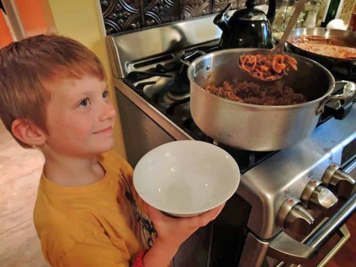 Small boy getting a helping of beefaroni.