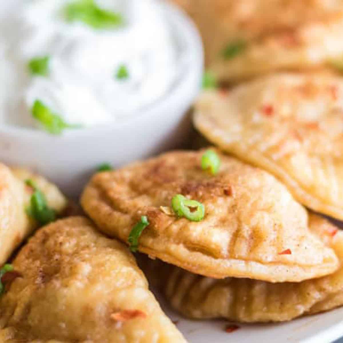 A plate of pierogi with bacon bits.