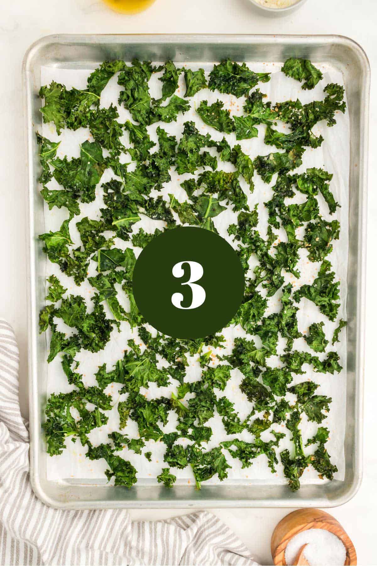 A baking sheet of kale chips with salt.