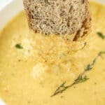 Dipping a slice of bread into a bowl of soup.