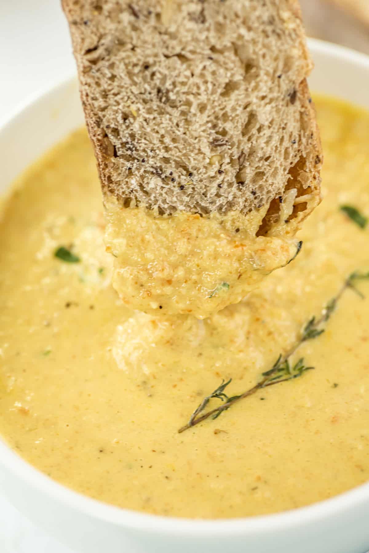 Dipping a big slice of bread into a bowl of soup.