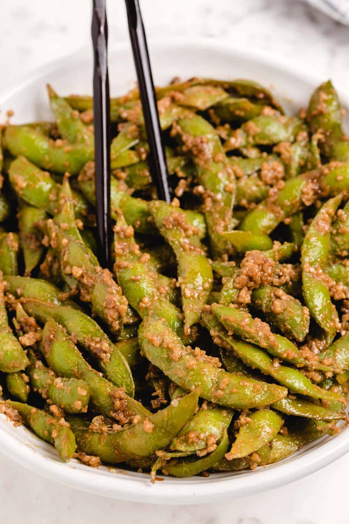 Grabbing some edamame from a large bowl.