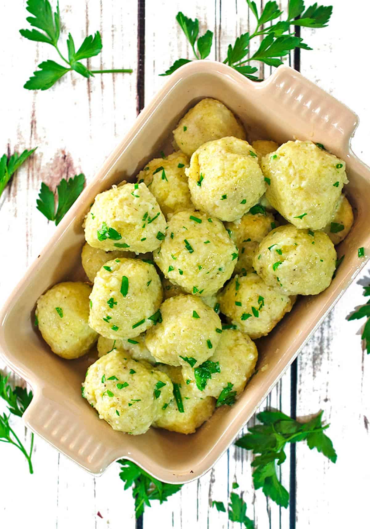 overhead view of a serving dish containing potato dumplings with Italian parsley garnish.