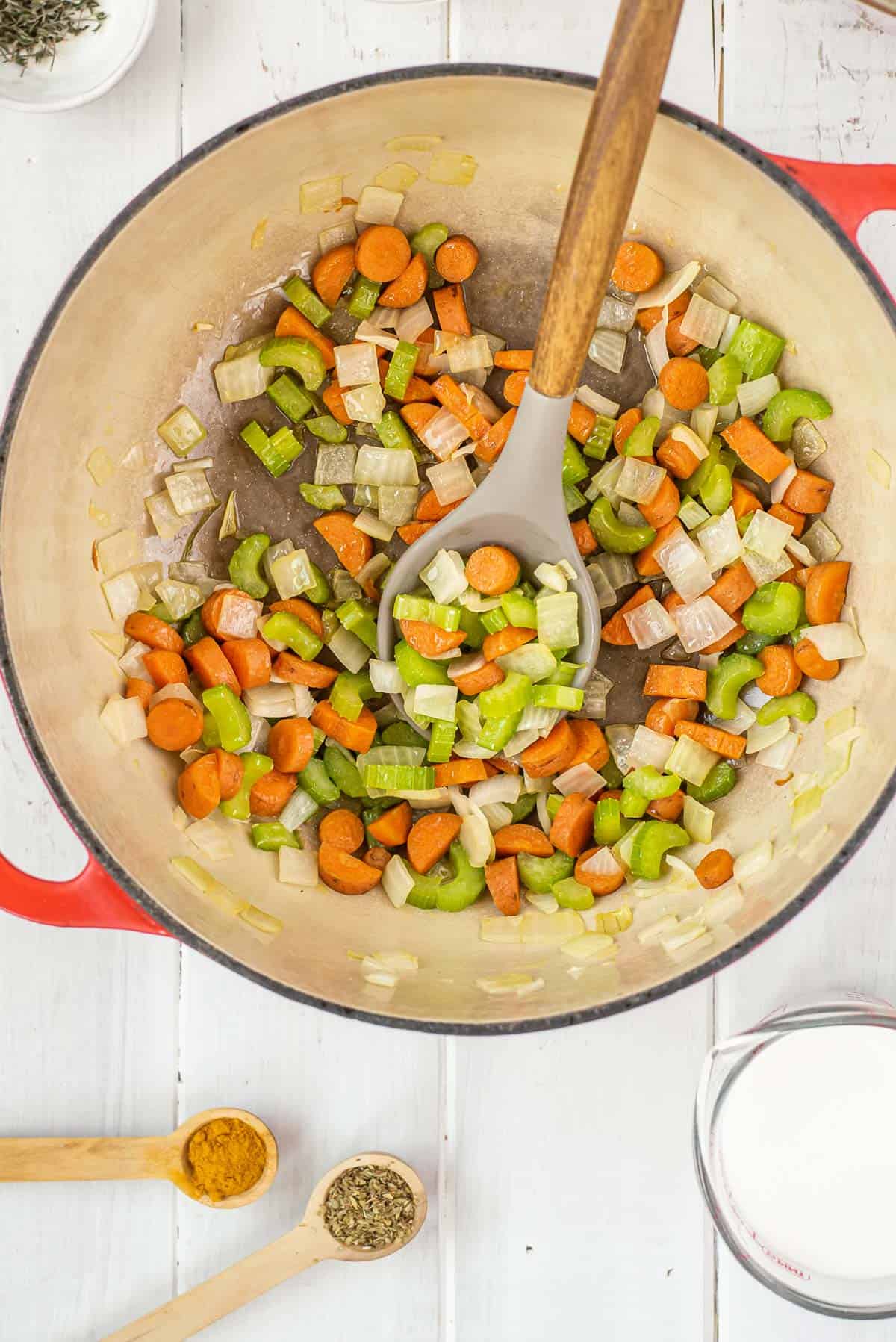 A pot of vegetables and a wodden spoon.