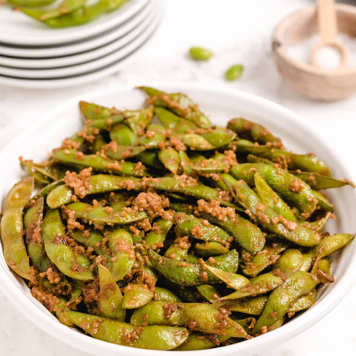 A big plate of edamamae pods covered in a garlic sauce.