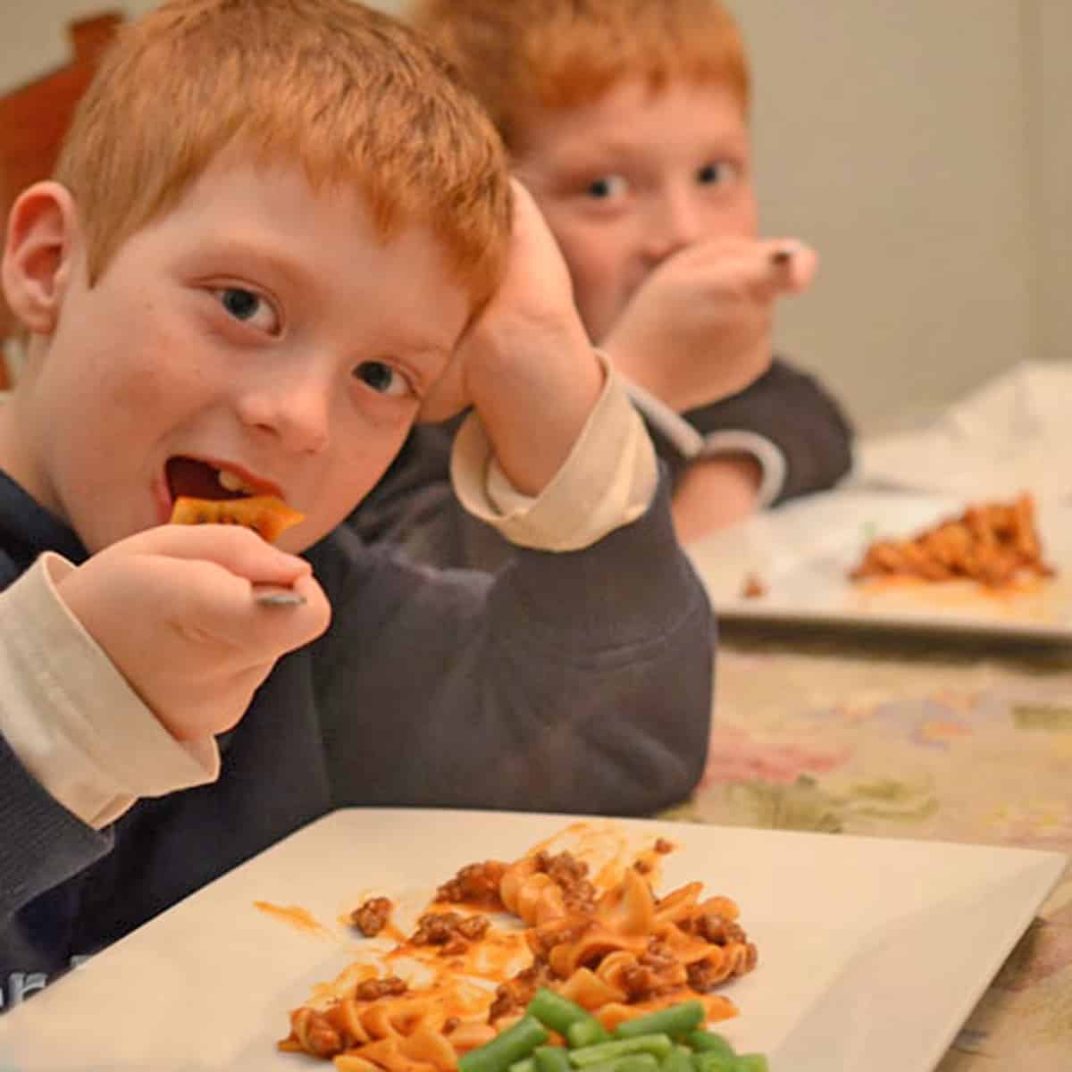 2 boys eating homemade beefaroni.