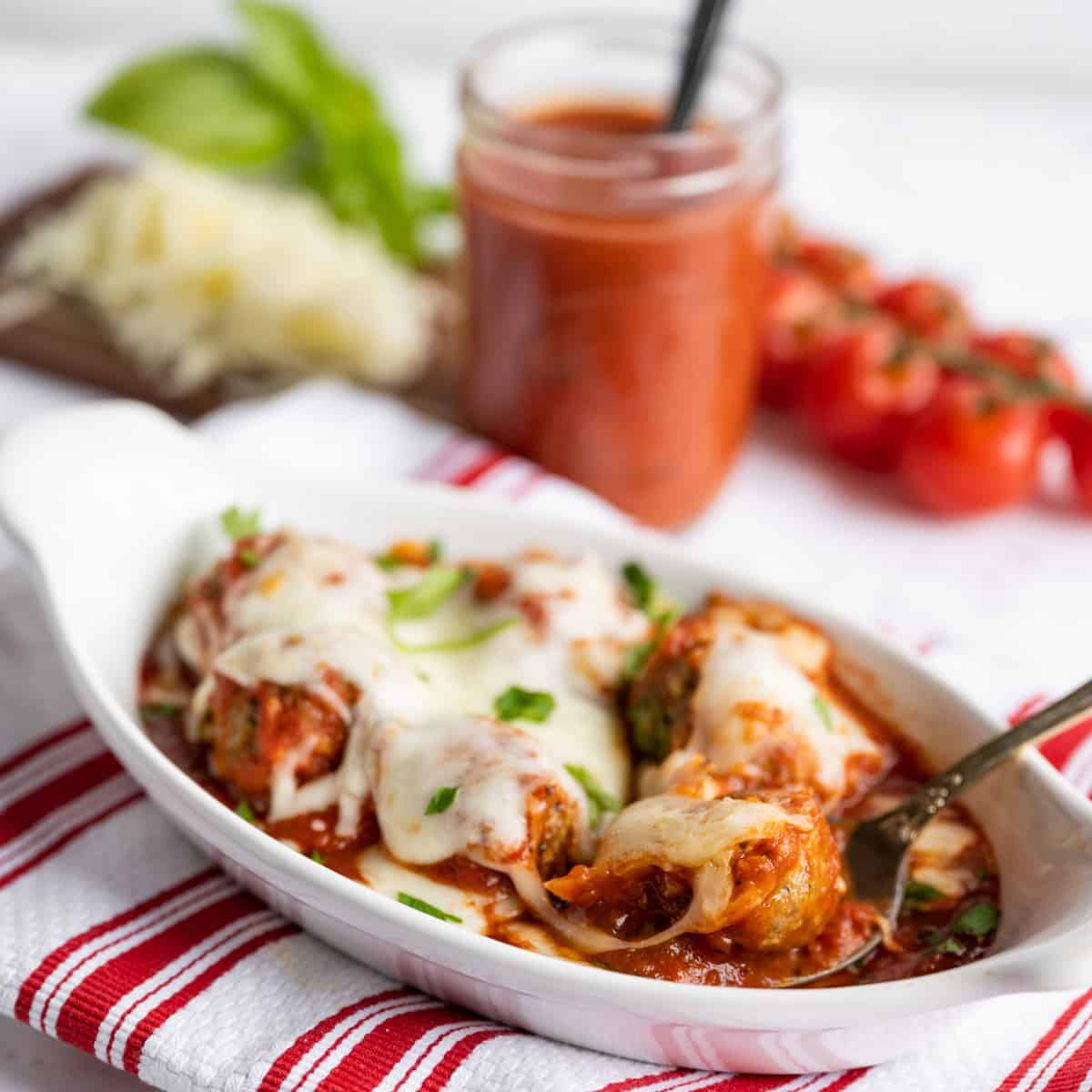 A dish of baked meatballs with marinara sauce.