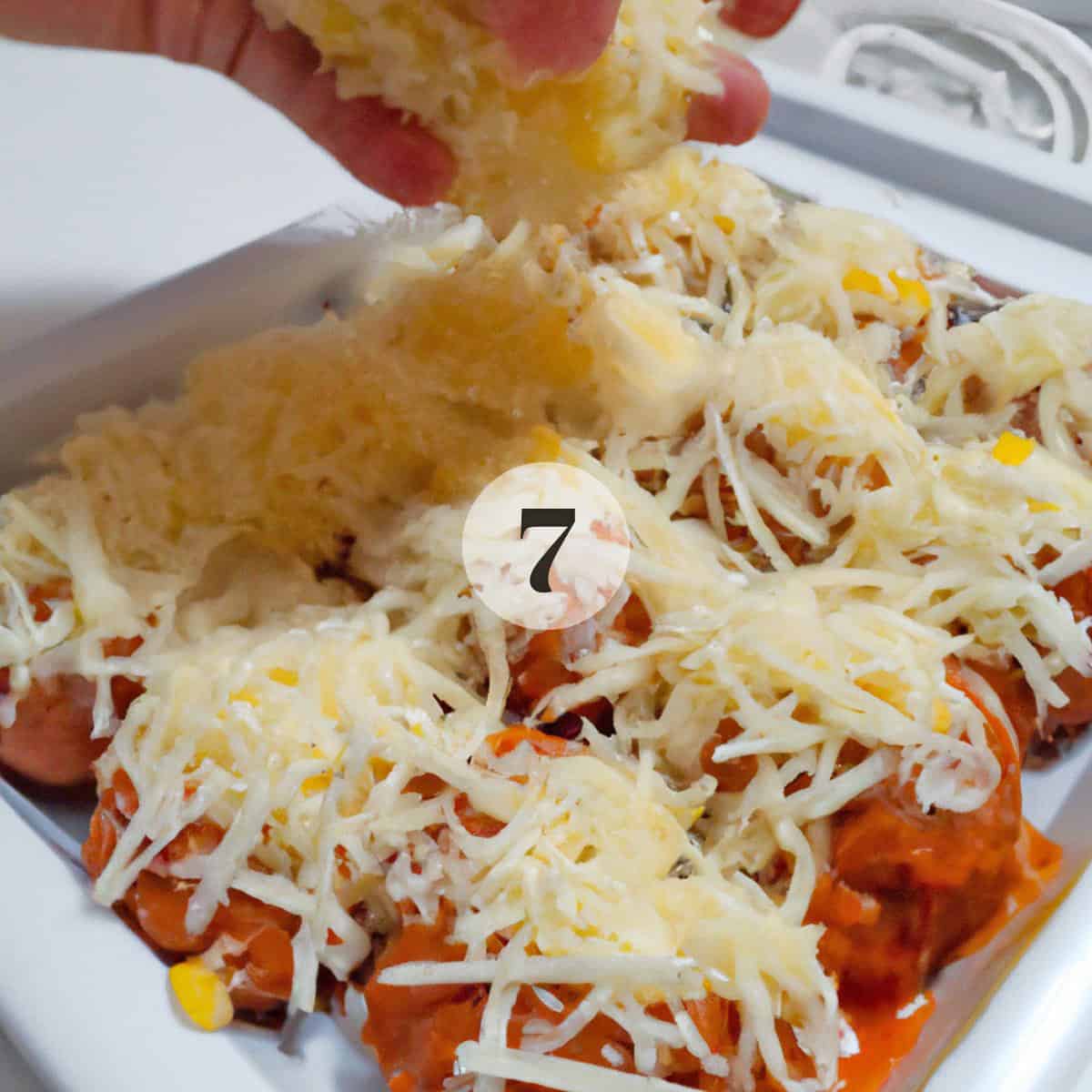 Adding shredded cheese to meatballs.
