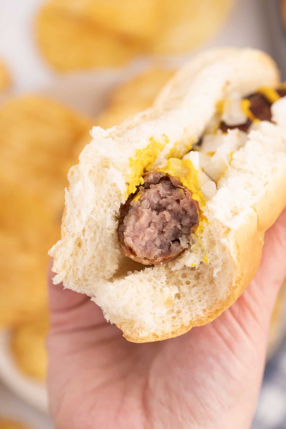 A brat in a roll with a bite taken out of it.