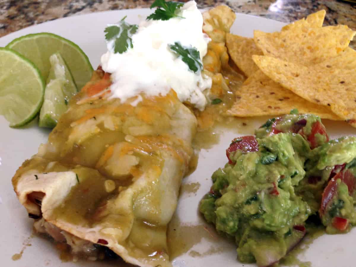 An enchilada on a plate with guacamole.