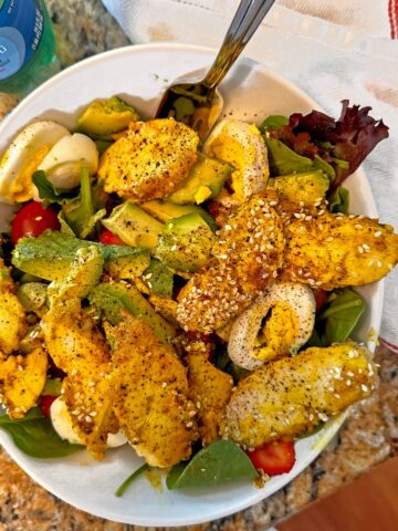 Overhead view of a turmeric chicken salad in a white bowl.
