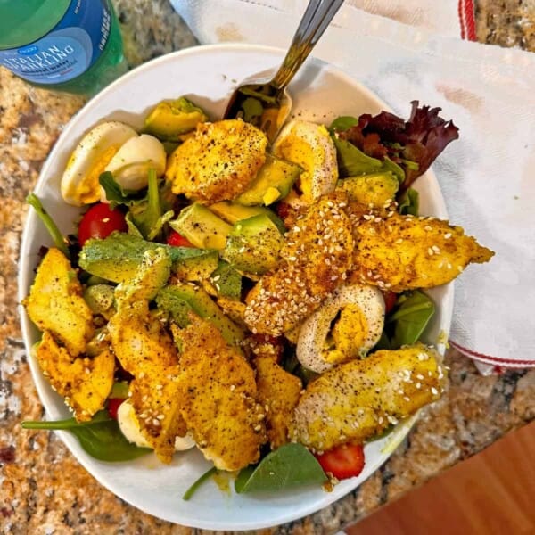 Overhead view of a turmeric chicken salad in a white bowl.