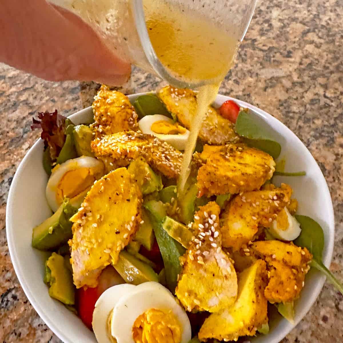 Pouring a vinaigrette dressing over a salad.