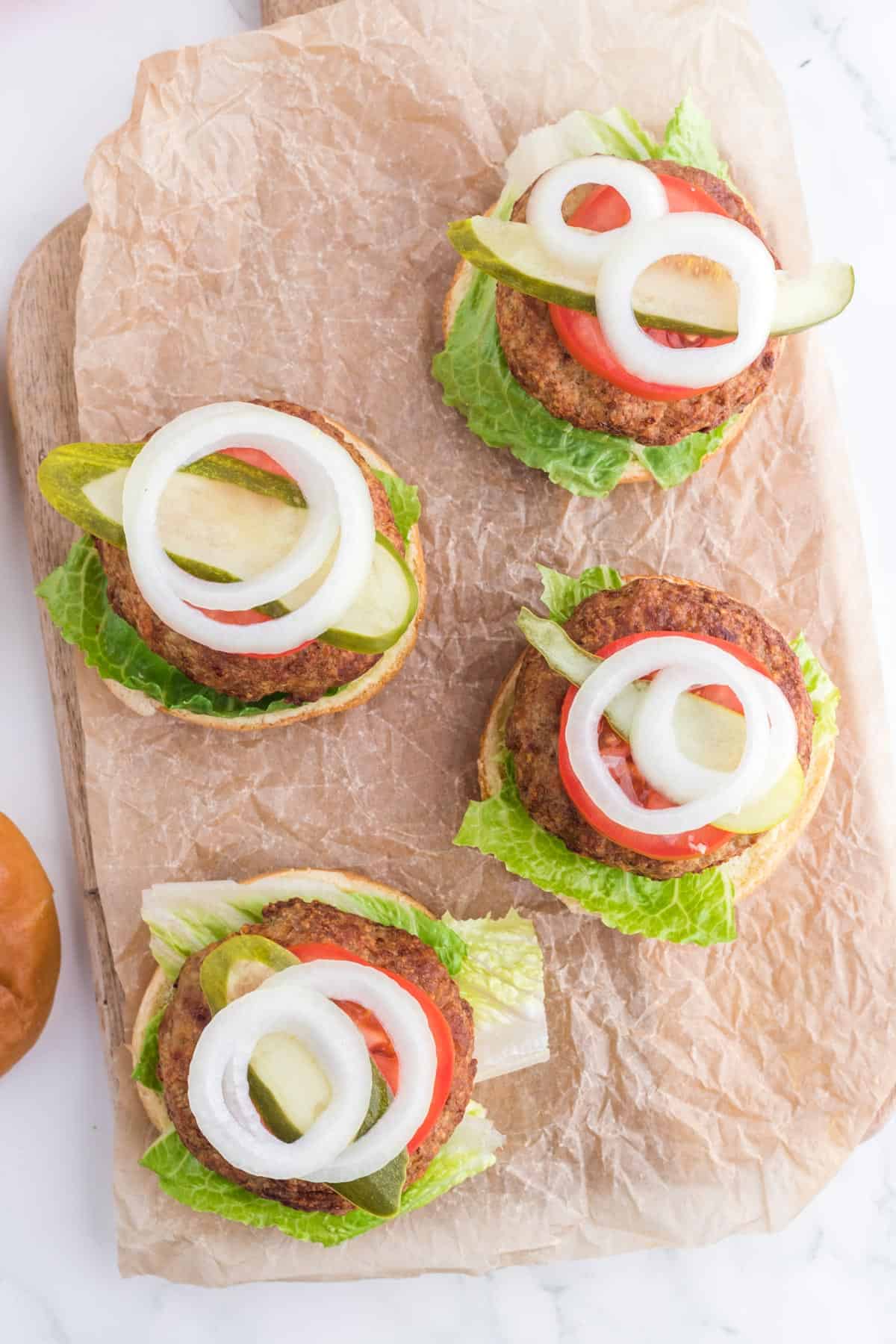 A group of burgers with toppings on them.