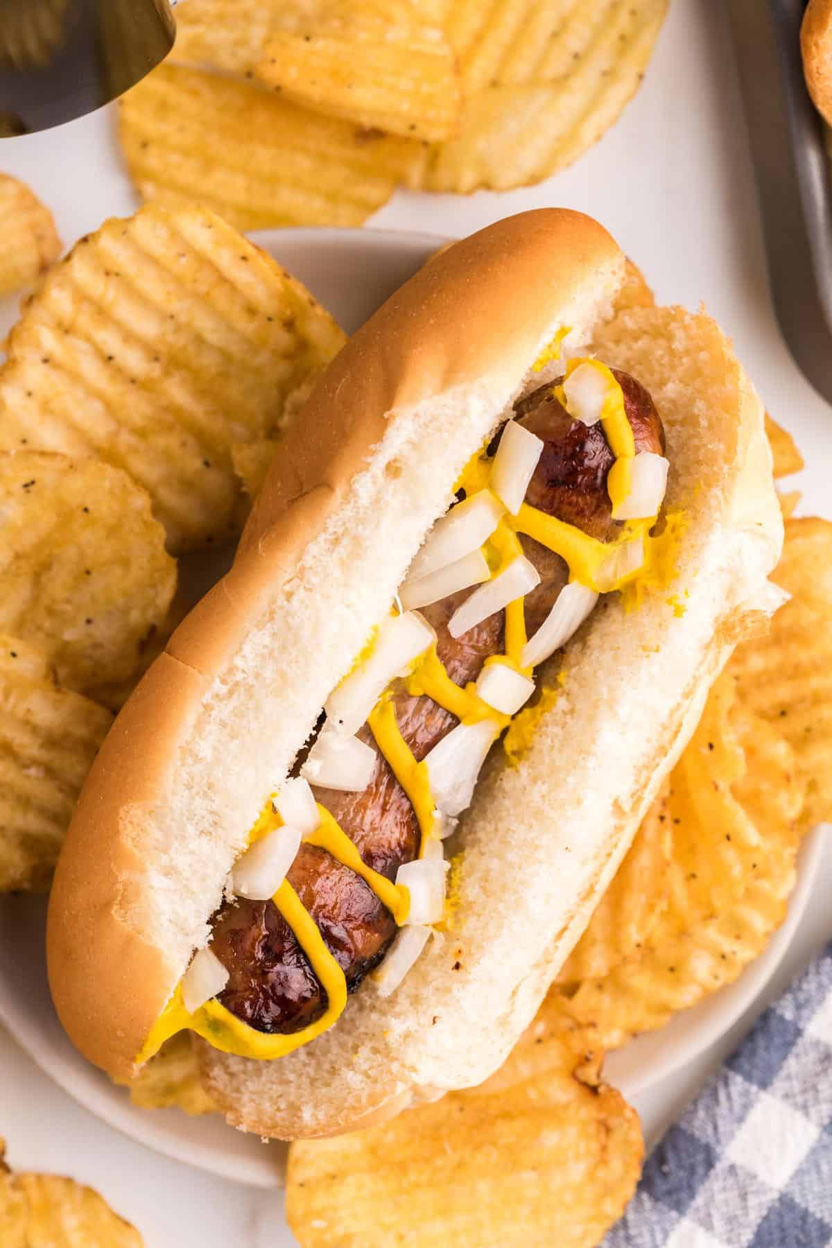 A brat in a roll with onion and mustard.