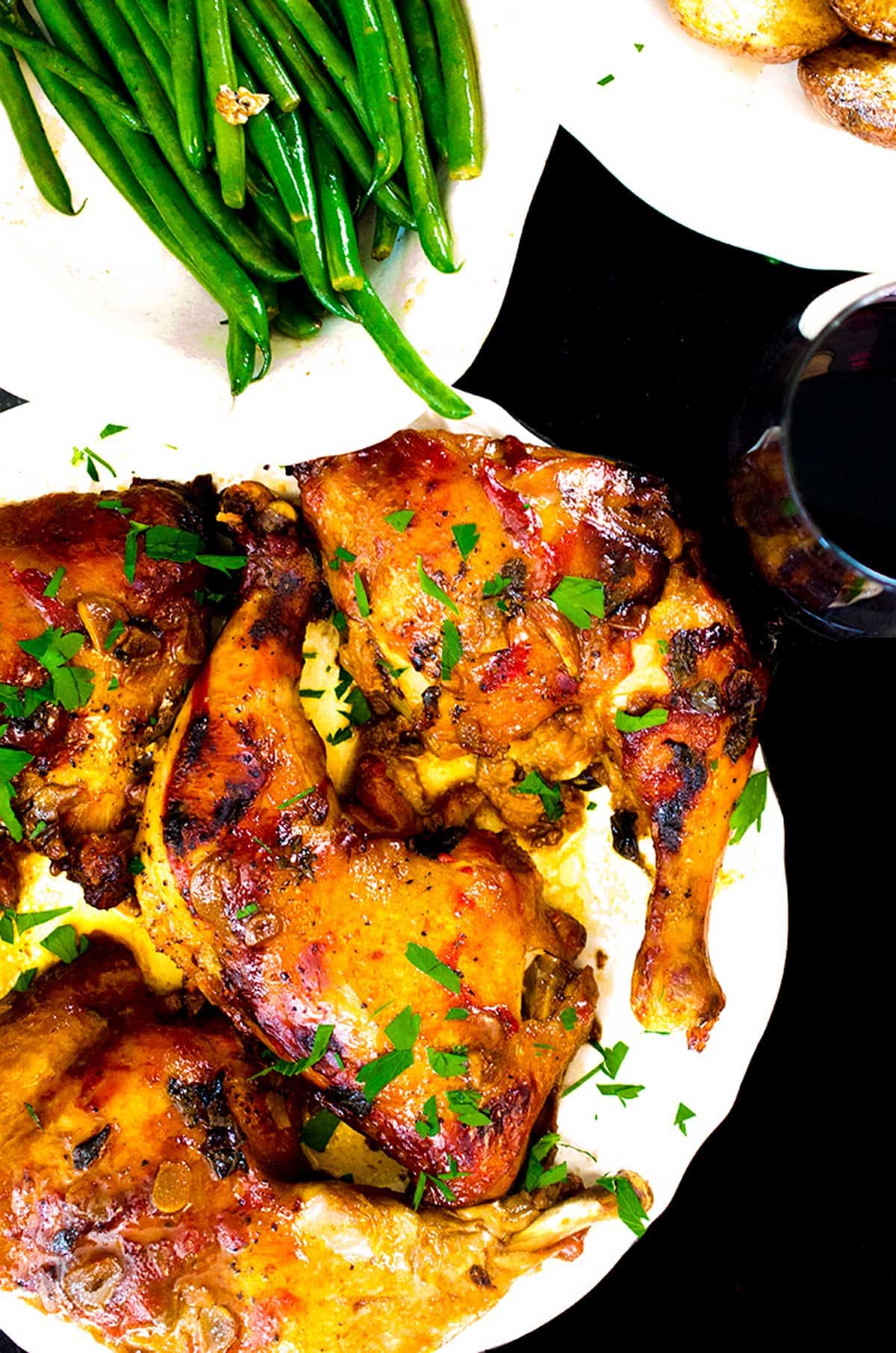 A plate of chicken leg quarters with some green beans on the side.